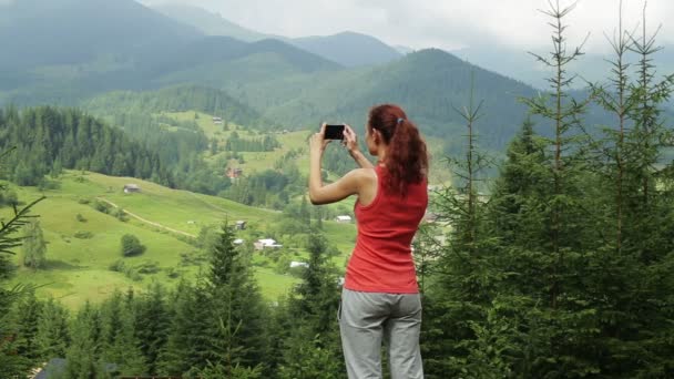 Το κορίτσι στα βουνά κάνει τη φωτογραφία στο τηλέφωνο. — Αρχείο Βίντεο