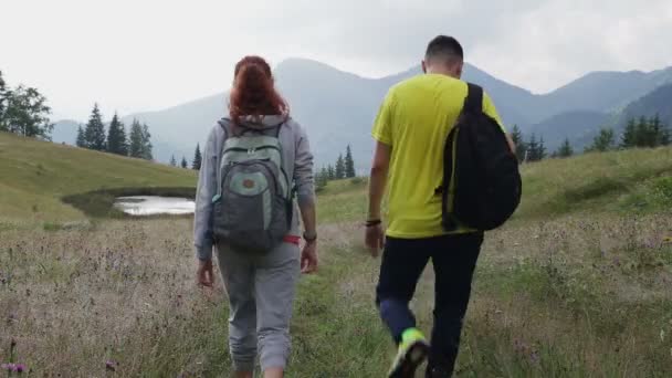 Çift Backpackers dağlarda yolda yürüyüş — Stok video