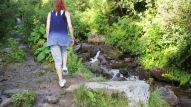 Uzun yürüyüşe çıkan kimse kadınla bir şelale orman iz arka planda dağlarda yürüyüş sırt çantası. Hiking. Ormanda macera.