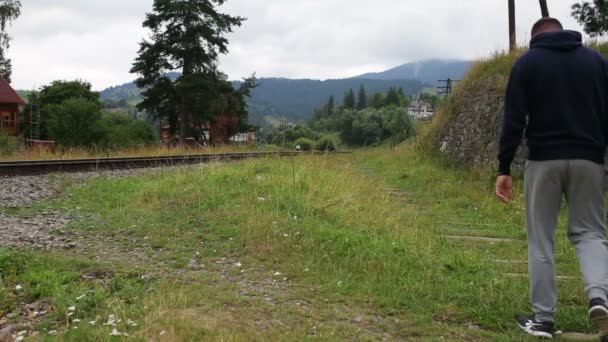 Schönes Paar spaziert gemeinsam auf Eisenbahn in den Bergen — Stockvideo