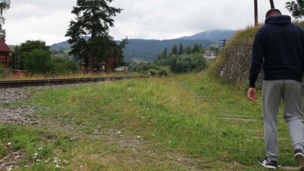 Hermosa pareja caminando en ferrocarril en las montañas juntos — Vídeos de Stock