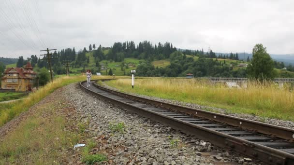 Belo casal andando na estrada de ferro em montanhas juntos — Vídeo de Stock