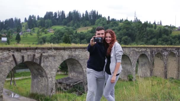 Ευτυχισμένο ζευγάρι κάνει selfie μπροστά από την παλιά οδογέφυρα — Αρχείο Βίντεο