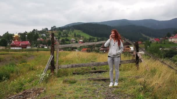 A lány beszél a telefonon, a hegyekben állt a viadukton — Stock videók