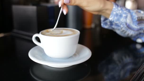 这个女孩在一杯咖啡搅拌糖。女手特写杯咖啡 — 图库视频影像