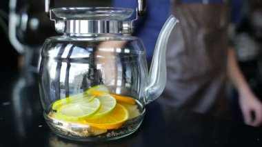 Barmen bir limon bir cam çaydanlık koyar.