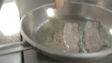 Üç bir tavada kızartma domuz pastırması şeritler.