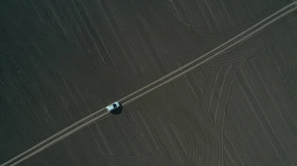 empty field top view, on a narrow road, a trail is symmetrically white car, graphic, geometric space, landscape abstraction