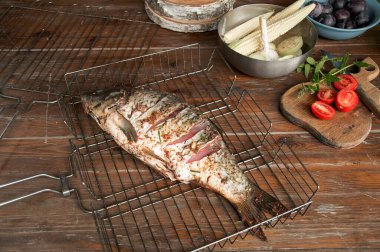 Limonlu ızgara balık, otlar ve baharatlar eski ahşap masa üzerinde. Pişirilmiş ızgara balık.