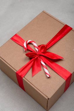 Beton arka planda kırmızı kurdeleli el yapımı Noel hediyesi kutusu.