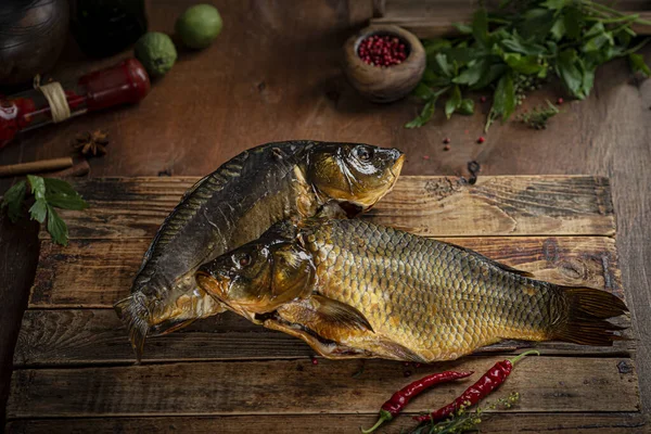 Cold smoked fish silver carp on a black board with herbs and onions