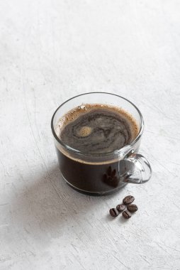 Açık arkaplanda şeffaf bir kupada sade kahve.