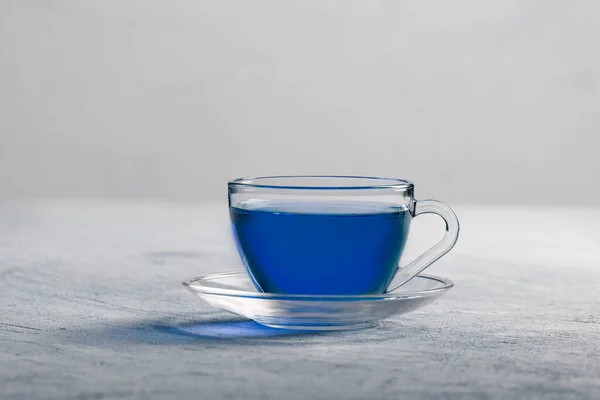 Πεταλούδα τσάι λουλούδι μπιζελιού παρασκευάζεται σε ένα ποτήρι τσαγιέρα και σερβίρεται σε ένα διαφανές κύπελλο. Μπλε τσάι βοτάνων. — Φωτογραφία Αρχείου