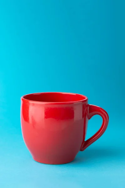 Kırmızı boş bir fincan çay, kahve, mavi arka planda. Metnin için yer.