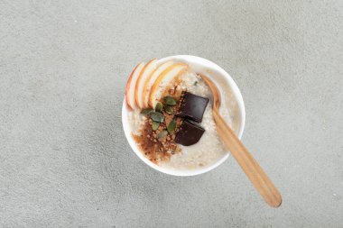 Kabak tohumlu yulaf ezmesi, tarçın ve gri arka planda çikolata. Sağlıklı kahvaltı manzarası