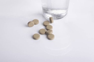 Bir bardak su, vitamin, hap ve tablet. Beyaz arkaplan.