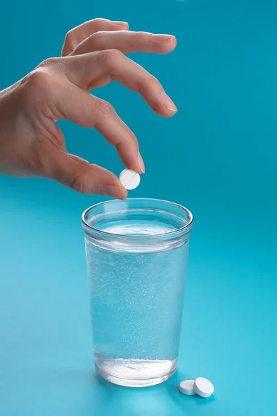 Glass of water and vitamins, pills and tablets. Light blue background.
