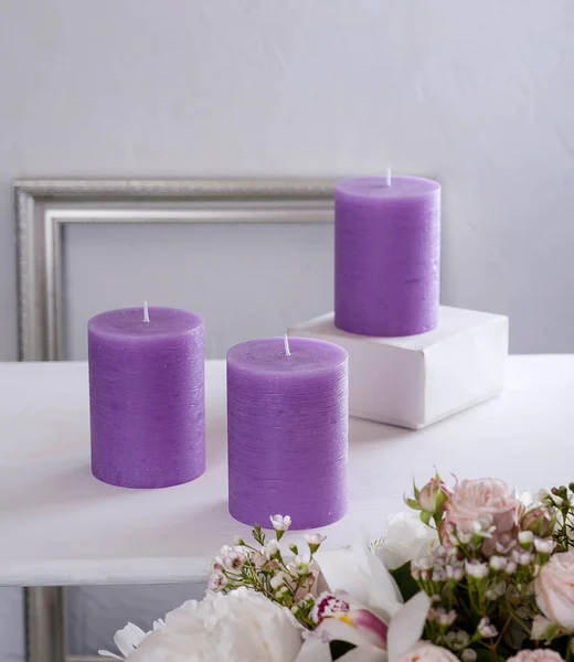 紫色的蓝色蜡烛 一束鲜花 放在白桌上 白色垂直背景 背景中的银框 — 图库照片