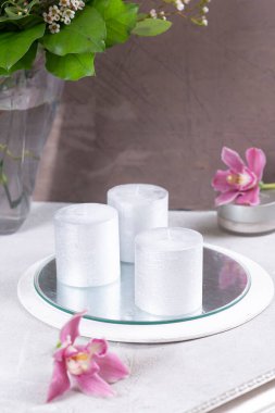 Masanın üzerinde gümüş mumlar ve bir çiçek var.