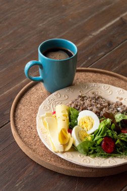 Kahveli sağlıklı kahvaltı. Yumurtalı salata, peynir, yulaf lapası ve kahveli çilek, ahşap bir masada..