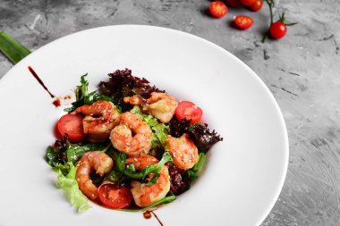 Beyaz tabakta kral karidesli yeşil salata, sağlıklı yemek konsepti. Açık gri arkaplan, yakın plan.