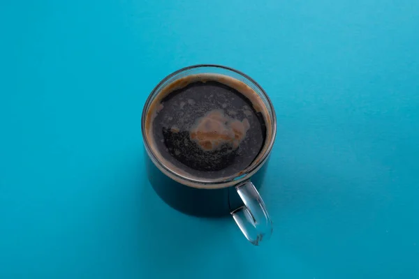 Glass cup of coffee with foam, on a blue background. — Stock Photo, Image