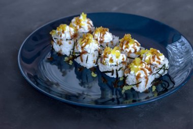 Japon suşisi yakın plan. Mavi bir plakanın yan görünümü, koyu gri desenli arka plan.