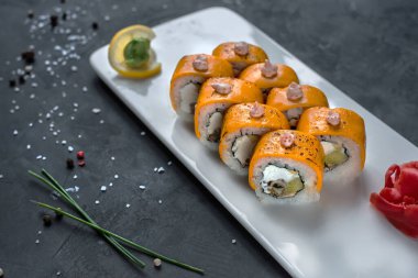 Japon suşisi yakın plan. Beyaz plaka üzerinde yan görünüm, koyu gri yatay arkaplan.