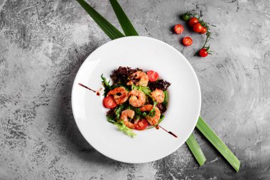 Beyaz tabakta kral karidesli yeşil salata, sağlıklı yemek konsepti. Açık gri arkaplan, üst görünüm.