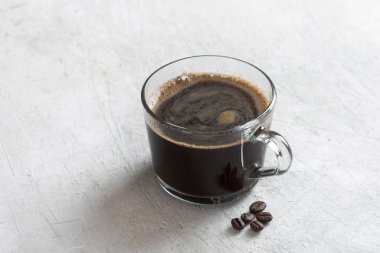 Açık arkaplanda şeffaf bir kupada sade kahve.