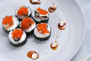 Japon suşisi yakın plan. Beyaz plaka üzerinde üst görünüm, açık gri arkaplan.