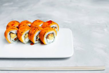 Japon suşisi yakın plan. Beyaz plaka üzerinde üst görünüm, açık gri arkaplan.