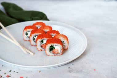 Japon suşisi yakın plan. Beyaz bir plakanın yan görünümü, açık gri desenli arkaplan.