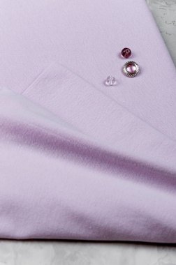 Leylak kumaşında boncuk. Doğal lif kumaşı. Açık gri dikey arkaplan.