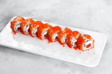 Japon suşisi yakın plan. Beyaz bir plaka üzerinde yan görünüm, açık gri yatay arkaplan.