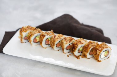 Japon suşisi yakın plan. Beyaz bir plaka üzerinde yan görünüm, açık gri yatay arkaplan.