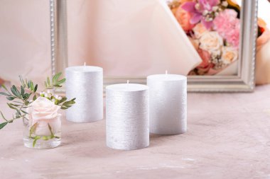 Masanın üzerinde gümüş mumlar ve bir çiçek var.