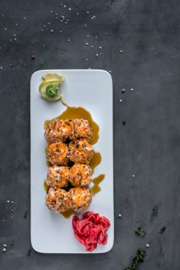 Japon suşisi yakın plan. Beyaz bir plaka üzerinde yan görünüm, koyu gri dikey arkaplan.