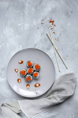 Japon suşisi yakın plan. Beyaz plaka üzerinde üst görünüm, açık gri arkaplan.