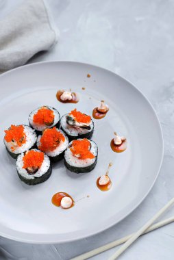 Japon suşisi yakın plan. Beyaz plaka üzerinde üst görünüm, açık gri arkaplan.