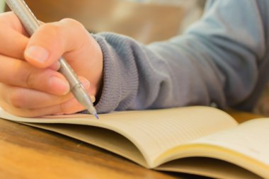 Not defterine kalem yazan kadın eller