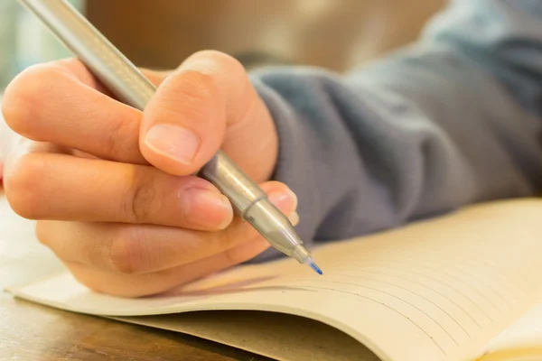 Žena ruce s perem psaní na notebook — Stock fotografie