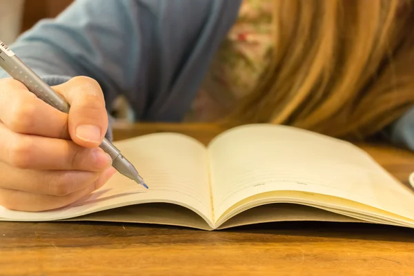 Mani femminili con scrittura a penna su taccuino — Foto Stock