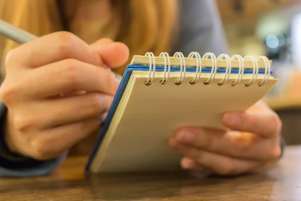 Žena ruce s perem psaní na notebook — Stock fotografie