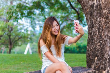 Asyalı kadın bir bahçe veya park Smartphone selfie oynarken