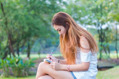 Asyalı kadın bir bahçe veya park, kitap yazma