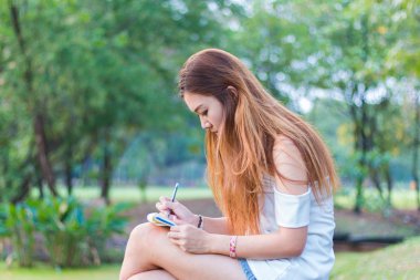 Asyalı kadın bir bahçe veya park, kitap yazma