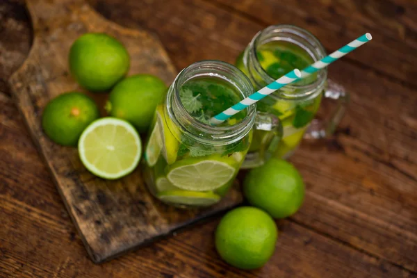 Fresh drink lemonade mojito in mason jar on wooden background. Mojitos with mint leaves, lime and ice, outdoor. — Stock Photo, Image