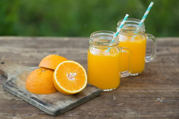 Taze portakal suyu ve ahşap masa üzerinde olgunlaşmış dilimlenmiş.