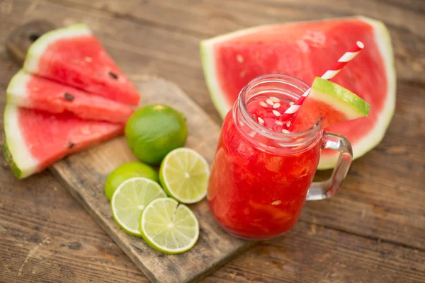 Wassermelonen-Smoothies mit Limette und Scheiben reif auf Holztisch. — Stockfoto